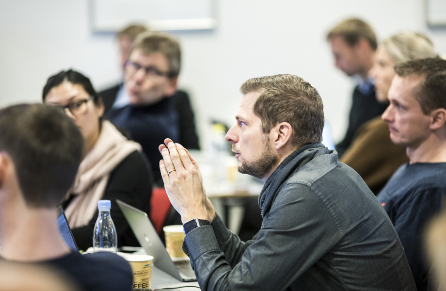Mand sidder i klasselokale, og er i gang med at sige noget i plenum. Rundt om sidder andre, og lytter på manden.